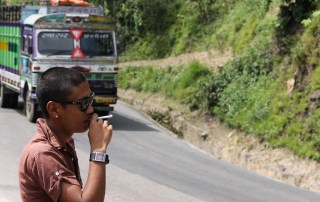 A man smokes on the side of the road as a bus passes in Nepal. Photo: World Bank/Aisha Faquir