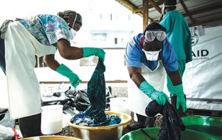 Health workers clean hospital scrubs and protective gear at the Island Clinic for Ebola treatment centre in Monrovia, Liberia, during the 2014 Ebola outbreak. USAID/Morgana Wingard