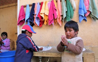 Photo: Two small children wash their hands in Bolivia.