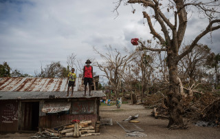 A child and an elderly man stand on the roof of a building damaged when Cyclone Pam hit Vanuatu in March 2015. Photo: UNICEF/Vlad Sokhin