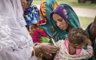 尼日尔一位妇女抱着患营养不良的孩子被带领到卫生中心进行治疗。粮食署图片/Chris Terry, supported by the EU