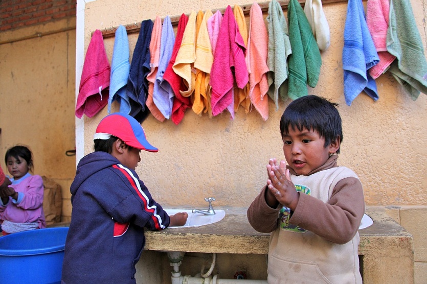 Dos niños se lavan las manos con jabón.