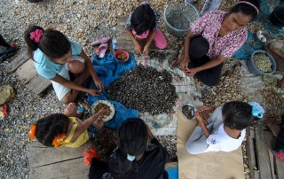 Una familia comiendo en el suelo. Foto OIT/Ferry Latief