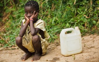 Photo: A little girl waits to fill her water container in the village of Kikonka, Bas-Congo province, Democratic Republic of Congo.