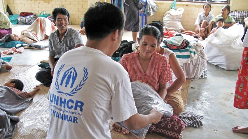 Une jeune victime du cyclone Nargis au Myanmar reçoit une couverture d'un membre du personnel du HCR, en 2008. 