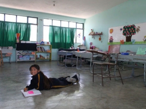 A girl drawing on the floor of her classroom