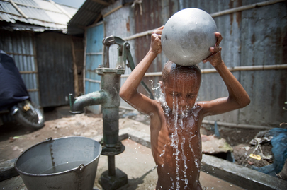 Un jeune garçon utilise une pompe à eau commune pour se laver. Photo ONU.