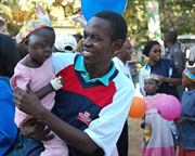 Sunday Nkwabi,National Secretary General-UNCTN carrying a baby living with cancer during Nelson Mandela International day, Muhimbili grounds, 17 July 2011.