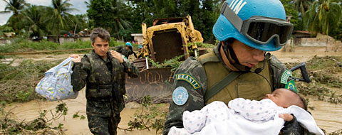 Miembros del personal de paz llevan a un bebé a un lugar seguro en un área inundada.