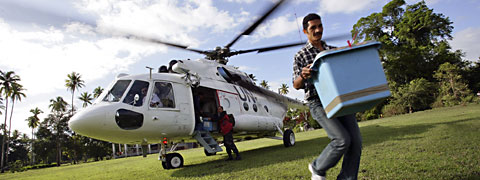 Un hombre lleva una caja grande de un helicóptero de la ONU.