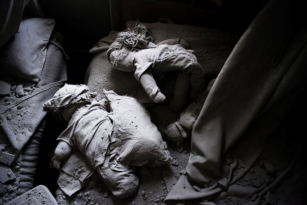 Des poupées d’enfants retrouvées dans les décombres d’une maison détruite par les bombardements, dans une ville touchée par le conflit en Syrie. Photo : UNICEF / Romenzi