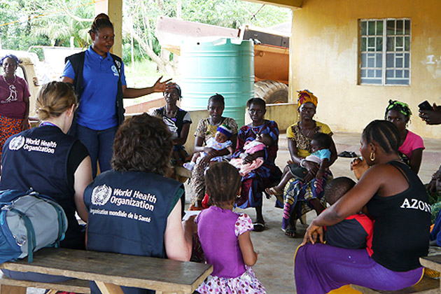 El brote de Ébola en Sierra Leona: el personal de la OMS habla con las madres sobre cómo acceder a la atención médica a los niños. Foto OMS/M. Harris