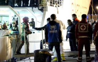 A UNHCR staff member watches as people rescued from the Mediterranean disembark from an Italian Coastguard vessel at Palermo, Sicily, on Tuesday 14 April 2015. Photo: UNHCR/F. Malavolta