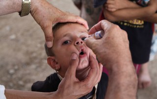 A health worker administers a dose of oral polio vaccine to a boy in the Bajeed Kandala camp in Iraq