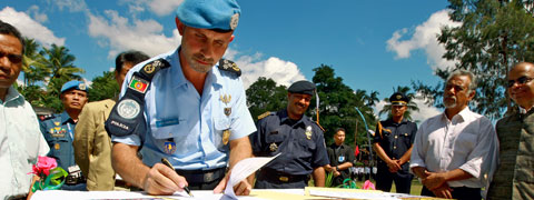 يوقع مفوض شرطة تابع للأمم المتحدة وثيقة وهو محاط بحفظة سلام آخرين وسكان محليين.