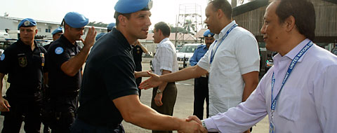 Personnel civil et personnel en uniforme de l'ONU se serrent la main.