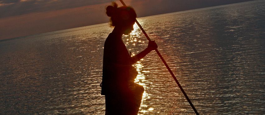 Une femme pêche au coucher du soleil