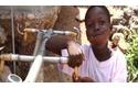 Niño haitiano bebiendo agua de una fuente de agua potable.