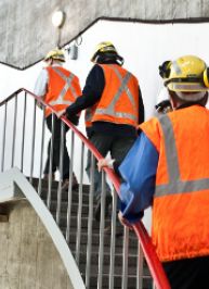 Workers wearing safety equipment ascending a staircase in a hydropower station