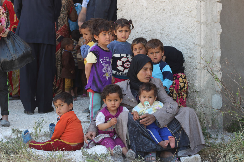 A woman and children wait outside a medical centre in Al-Radwanieh village, rural Aleppo, Syria. Photo: UNICEF/Khouder Al-Issa