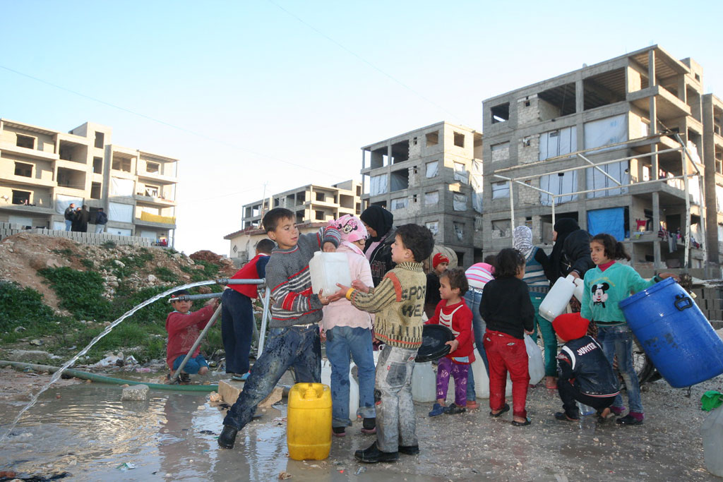 Children collect water at the Al-Riad shelter, Aleppo, Syria. Photo: OCHA/Josephine Guerrero
