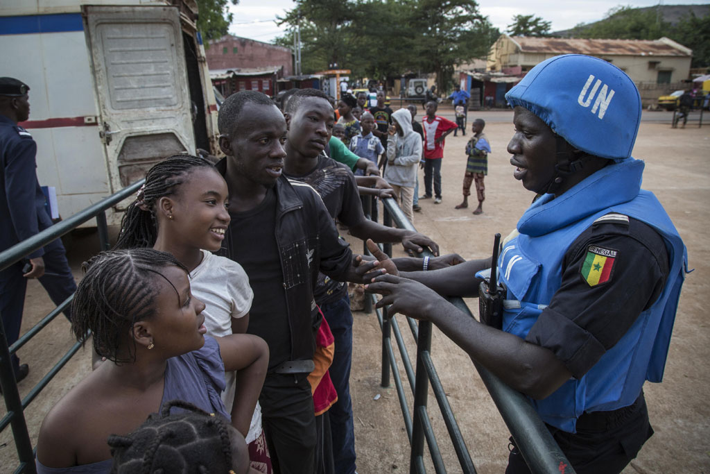 Senegalese peacekeepers from the UN Multidimensional Integrated Stabilization Mission in Mali (MINUSMA) Formed Police Unit (FPU) speak with Malians while they patrol outside Mamadou Konate Stadium during an event to promote peace among the youth. UN Photo/Marco Dormino