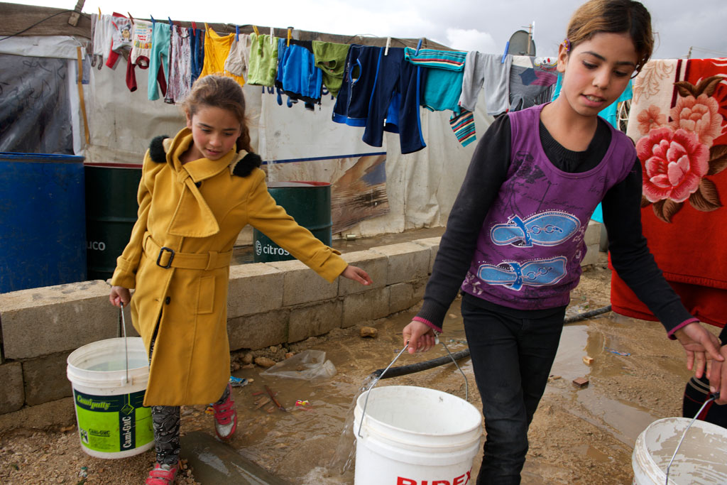Children use large, plastic buckets to collect drinking water from a nearby water point, in the Fayda informal tented settlement, in the Bekaa Valley, Lebanon. Photo: UNICEF/Shehzad Noorani
