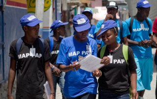 Participants in the Voices of Youth Maps initiative wearing T-shirts with the slogan ''MAP PAP'' (Port-au-Prince) as they walk on a street in the Village de Dieu neighbourhood.
