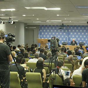 A wide view of the press briefing room as Vitaly I. Churkin (shown on screens), Permanent Representative of the Russian Federation to the UN and President of the Security Council for June, addresses journalists on the Council's work programme for the month. UN Photo/Paulo Filgueiras