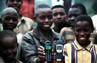 Chilldren using cellular phones in Rwanda with background of children playing