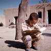 Young child reading in a copy book, street scene, child revising lesson, readin