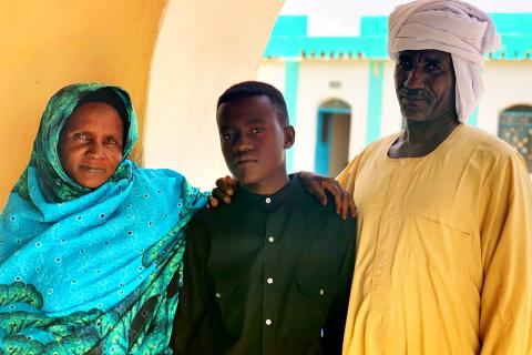 Sudan. A boy stands with his family.