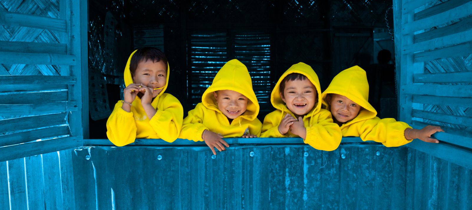 Four children look out an open window, Bangladesh