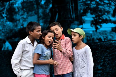 Four children look at a mobile phone