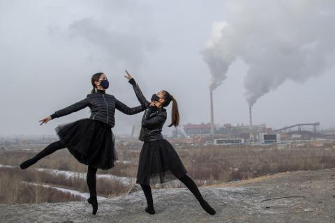 Mongolia: Two ballet dancers wearing masks strike a pose with factory chimneys behind them. 