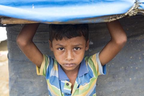 Bangladesh. A child stands under the plastic roof of a shelter in a refugee camp in Cox’s Bazar.