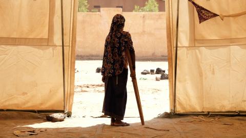 Mali. A girl stands using a crutch.