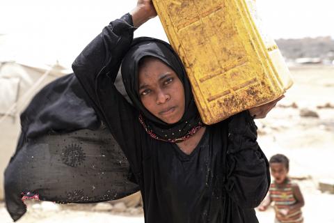 A girl carries a jerry can on her shoulder, Yemen