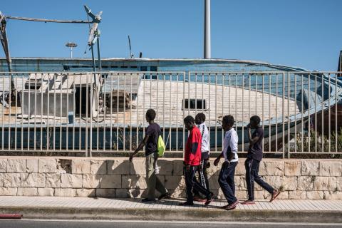Refugee and migrant boys walk past abandoned ships in in Pozzallo, Sicily, in 2016. 