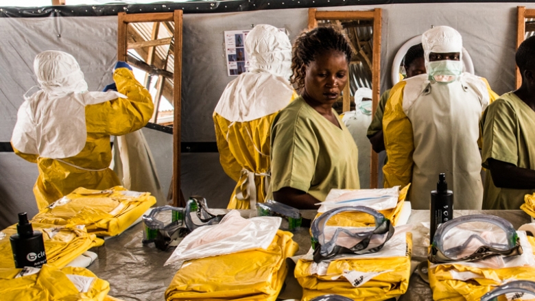 Health workers put their Personal Protective Equipment on before entering the zone where people suspected of having Ebola are held in quarantine to be monitored and treated at the Ebola Transition Center. © Vincent Tremeau/World Bank