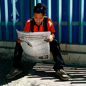 Young man reading newspaper in Dili, Timor-Leste. Photo by Martine Perret.