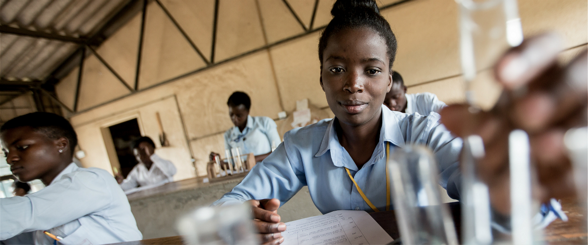 An adolescent girl conducts an experiment during a chemistry class