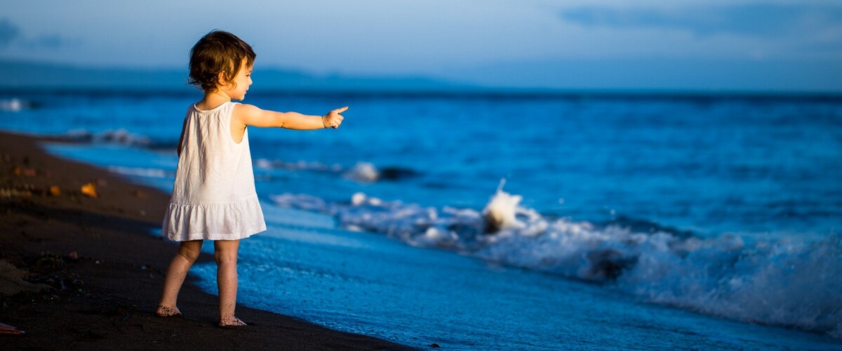 A little girl speaks to the ocean.