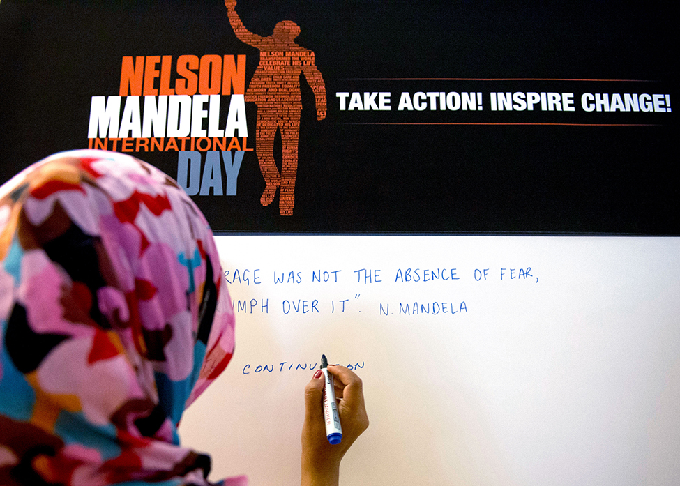 A participant writing a message on a board in commemoration of Nelson Mandela International Day.