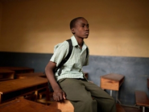A kid sitting in an empty classroom