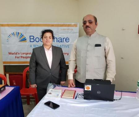 Zainab stands in front of a Bookshare Banner with Dr. Homiyar Mobedji, Bookshare Africa/India Head