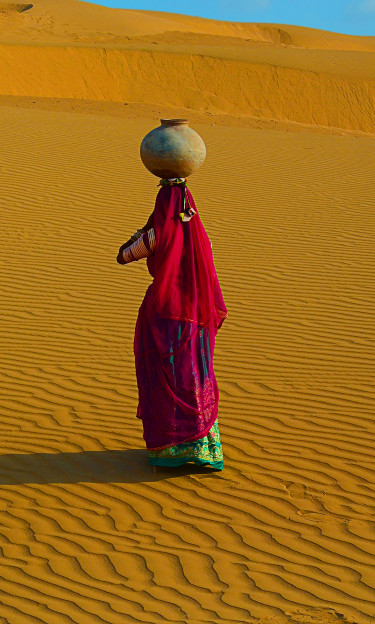 An Indian woman carrying a large jug of water on her head