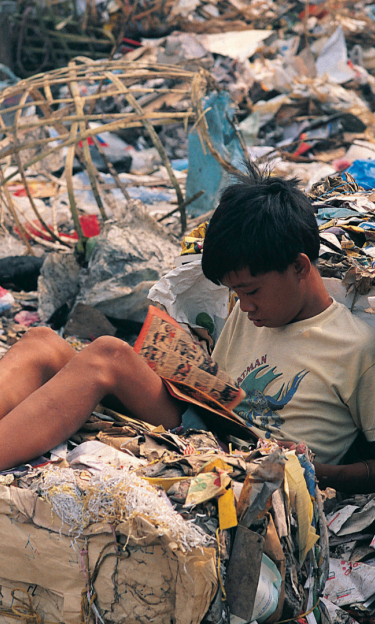 boy reading a book in a landfill