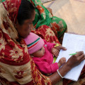 Bangladeshi mother writing with baby