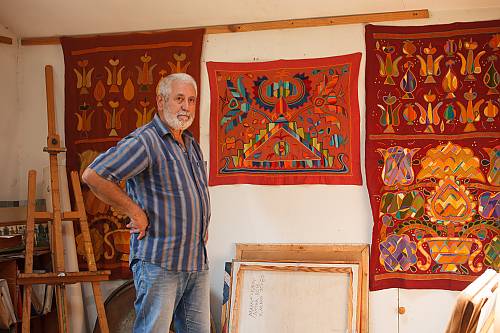 Mamut Churlu, the leader of 'Chatyr Dag' informal cultural association, in his artist's studio presenting embroidered panels based on Ornek ornaments.